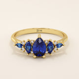 14k gold anniversary ring featuring five pear-cut sapphire gemstones. Elegant and symmetrical gemstone band design.