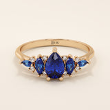 14k gold anniversary ring featuring five pear-cut sapphire gemstones. Elegant and symmetrical gemstone band design.