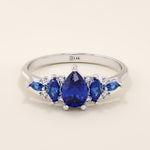 14k gold anniversary ring featuring five pear-cut sapphire gemstones. Elegant and symmetrical gemstone band design.