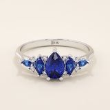 14k gold anniversary ring featuring five pear-cut sapphire gemstones. Elegant and symmetrical gemstone band design.