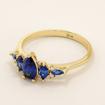 14k gold anniversary ring featuring five pear-cut sapphire gemstones. Elegant and symmetrical gemstone band design.