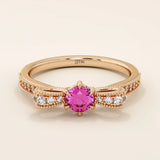 14k gold ribbon-shaped ring with a vibrant lab-grown ruby at the center. Elegant and romantic design with gemstone sparkle.