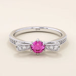 14k gold ribbon-shaped ring with a vibrant lab-grown ruby at the center. Elegant and romantic design with gemstone sparkle.