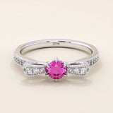 14k gold ribbon-shaped ring with a vibrant lab-grown ruby at the center. Elegant and romantic design with gemstone sparkle.