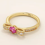 14k gold ribbon-shaped ring with a vibrant lab-grown ruby at the center. Elegant and romantic design with gemstone sparkle.