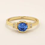 14k gold ring featuring a half bezel round sapphire with baguette moissanite accents. A modern gemstone anniversary band with elegant sparkle.