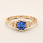14k gold ring featuring a half bezel round sapphire with baguette moissanite accents. A modern gemstone anniversary band with elegant sparkle.