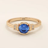 14k gold ring featuring a half bezel round sapphire with baguette moissanite accents. A modern gemstone anniversary band with elegant sparkle.
