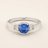 14k gold ring featuring a half bezel round sapphire with baguette moissanite accents. A modern gemstone anniversary band with elegant sparkle.