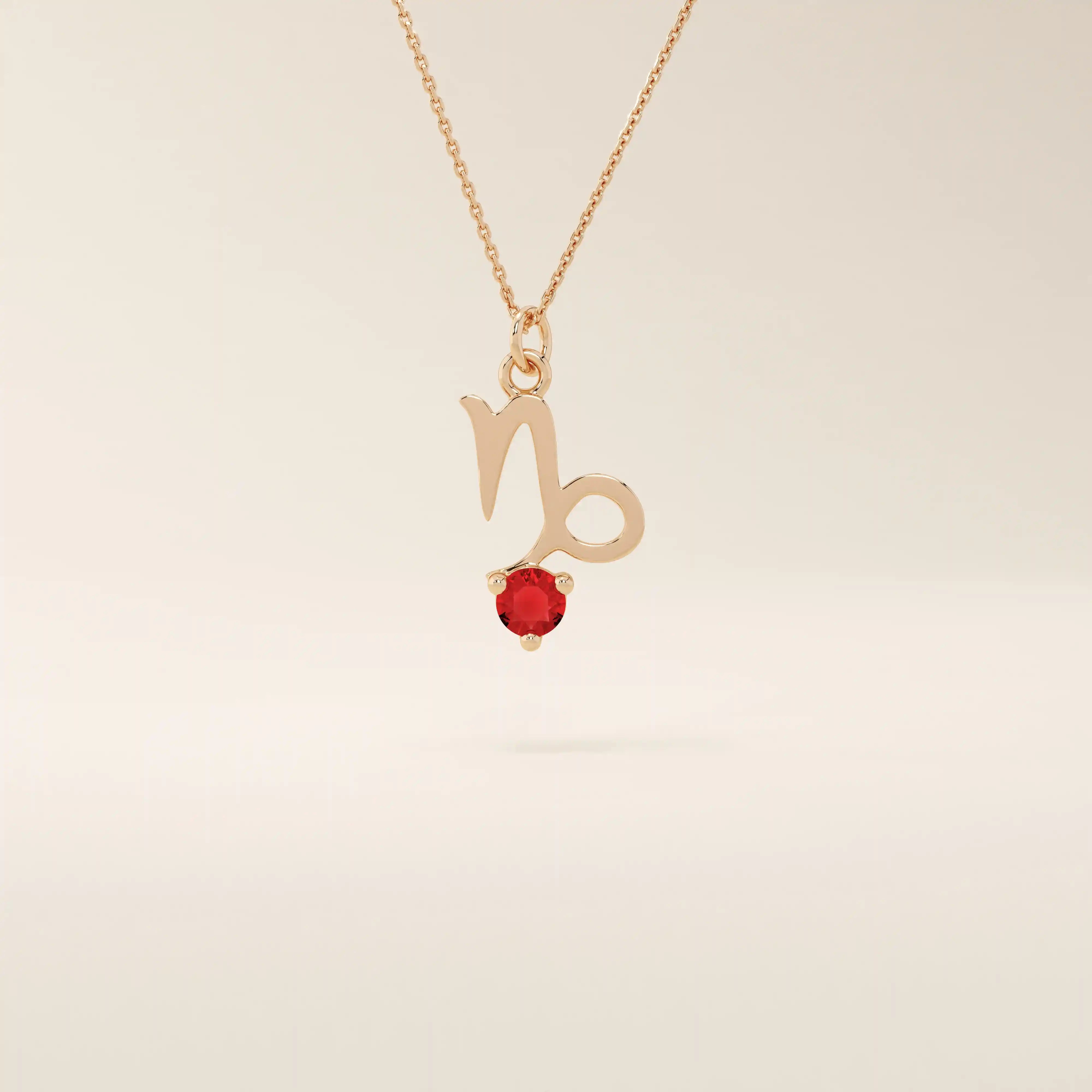 14k solid gold Capricorn symbol pendant necklace featuring a deep red garnet birthstone. A meaningful zodiac necklace perfect for personalized gifting.