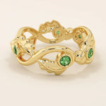 14k solid gold leaf vine band ring with a bezel-set emerald gemstone. Nature-inspired statement design.