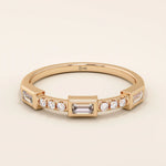 14k solid rose gold ring showcasing a baguette cut moissanite center stone with round brilliant cut moissanite accents, contemporary bezel and prong fine jewelry