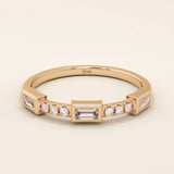 14k solid rose gold ring showcasing a baguette cut moissanite center stone with round brilliant cut moissanite accents, contemporary bezel and prong fine jewelry