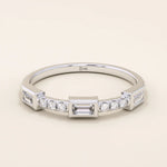 14k solid white gold band with a baguette cut moissanite center stone framed by round brilliant cut moissanite side stones, sleek bezel and prong setting design