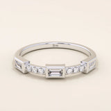 14k solid white gold band with a baguette cut moissanite center stone framed by round brilliant cut moissanite side stones, sleek bezel and prong setting design