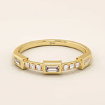 14k solid yellow gold band featuring a baguette cut moissanite center stone flanked by round brilliant cut moissanite accents, modern bezel and prong setting fine jewelry