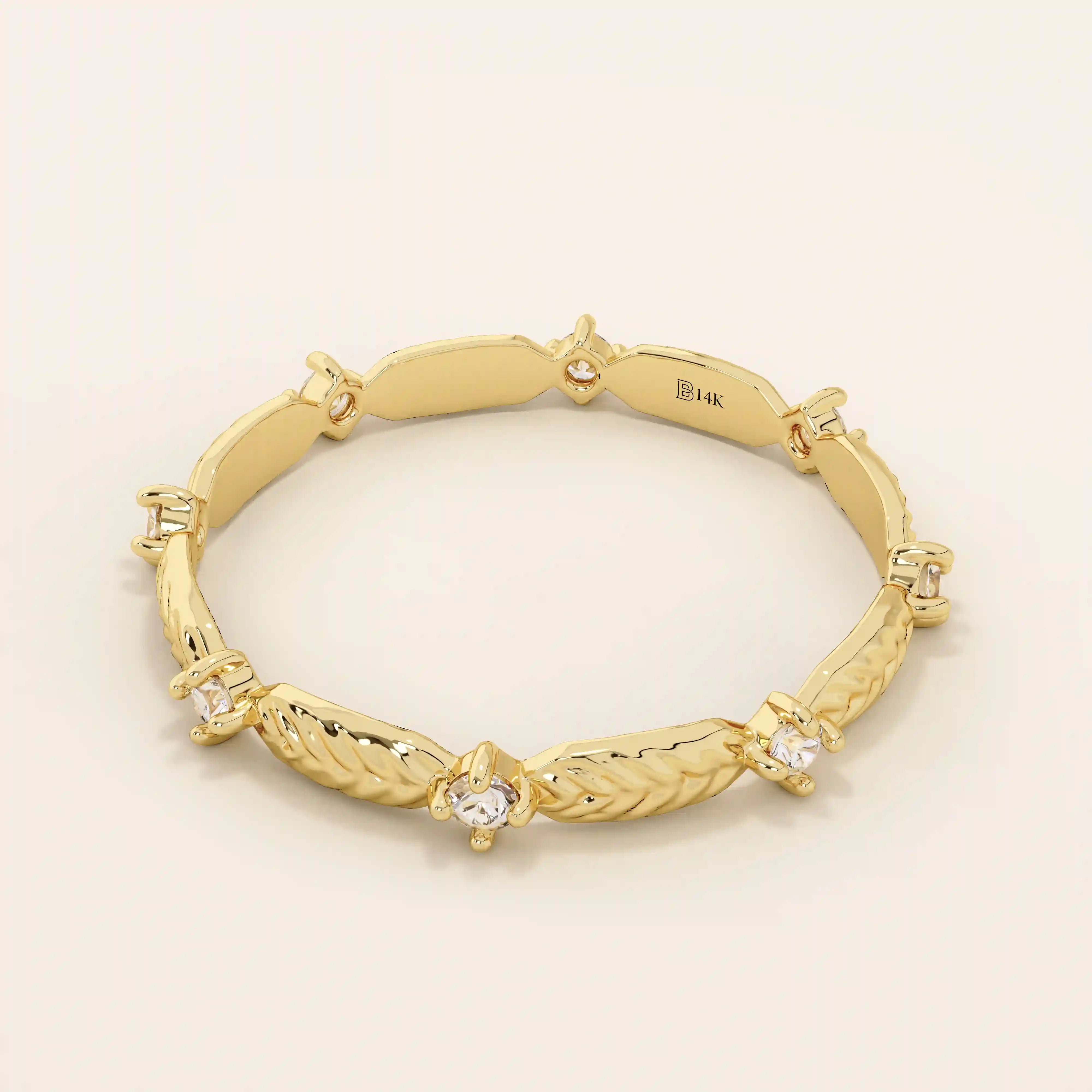 Angled view of a 14k yellow gold band showcasing alternating moissanite stones and polished leaf designs.