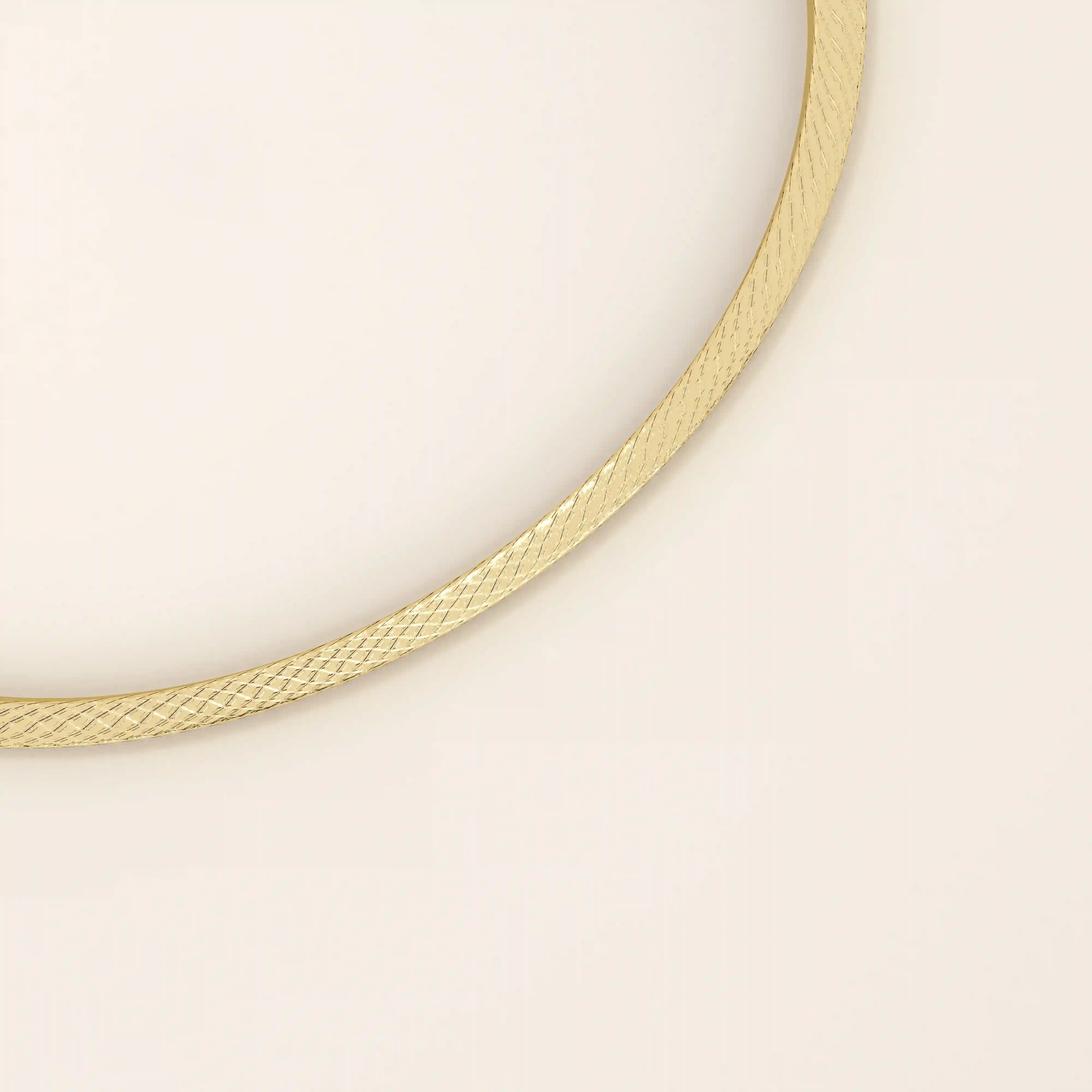 Angled view of a 14k yellow gold textured square tube bangle highlighting its slim tubular form and shimmering surface detail.