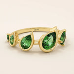 Bold 14k gold ring with five pear-cut emerald gemstones. A vibrant and eye-catching statement ring with rich green tones.