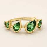Bold 14k gold ring with five pear-cut emerald gemstones. A vibrant and eye-catching statement ring with rich green tones.