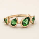 Bold 14k gold ring with five pear-cut emerald gemstones. A vibrant and eye-catching statement ring with rich green tones.