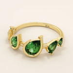 Bold 14k gold ring with five pear-cut emerald gemstones. A vibrant and eye-catching statement ring with rich green tones.