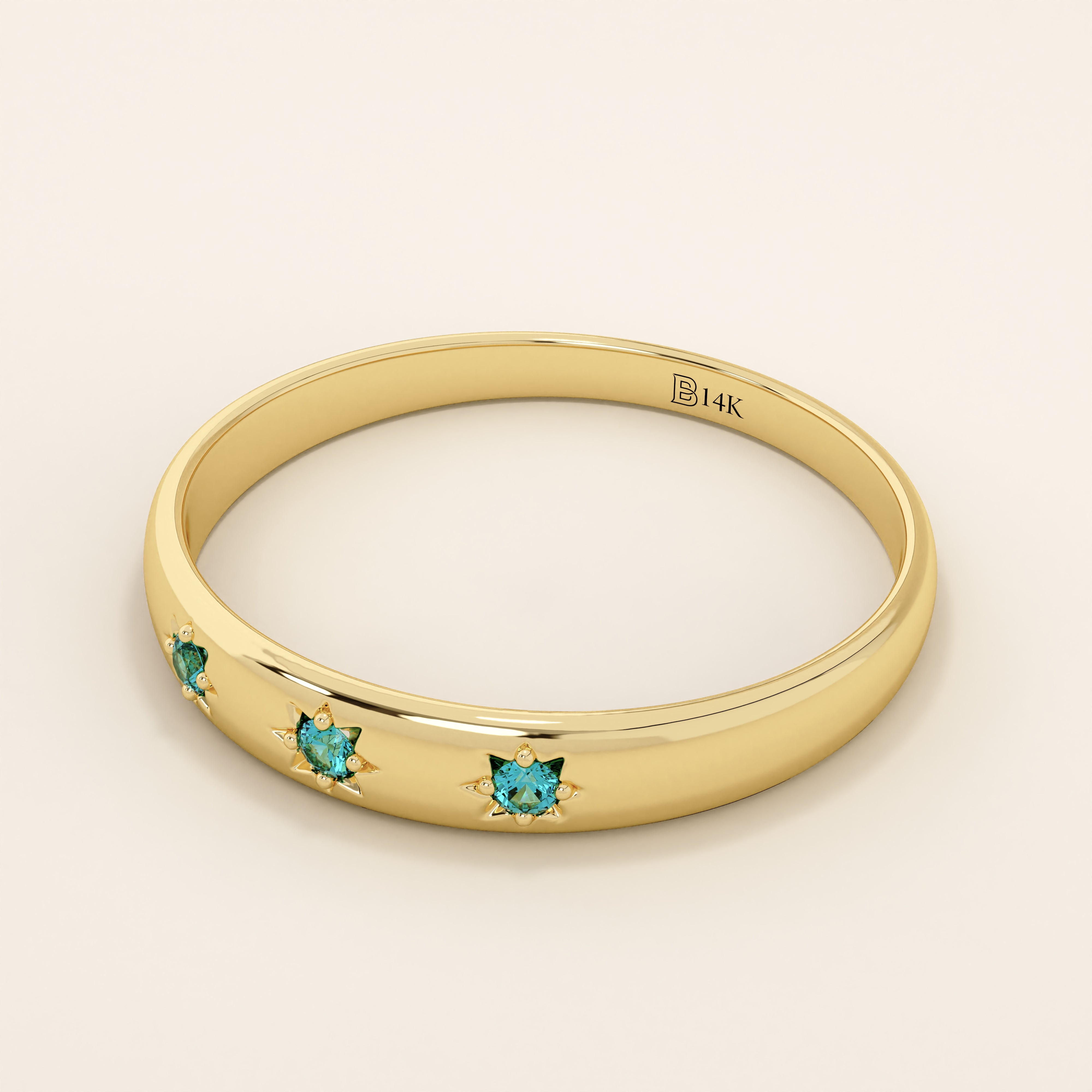 Close-up of a model’s hand wearing a 14k yellow gold dome ring with aquamarine gemstones in starburst settings across the band.