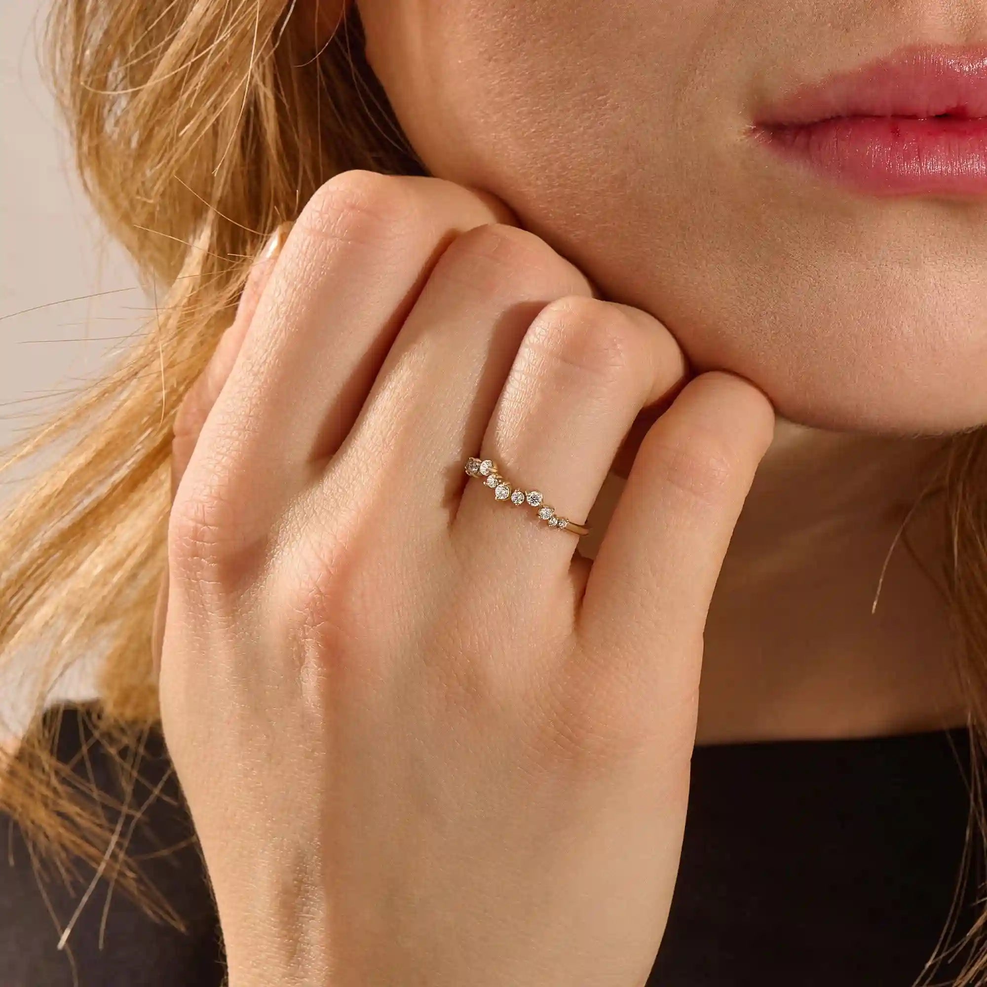 Close-up of a model’s hand wearing a 14k yellow gold pavé ring with alternating moissanite stone sizes.