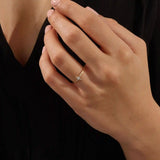 Close-up of a model’s hand wearing a 14k yellow gold starburst ring with moissanite center and accent stones.