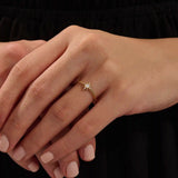 Close-up of a model’s hand wearing a 14k yellow gold starburst ring with moissanite center and accent stones.