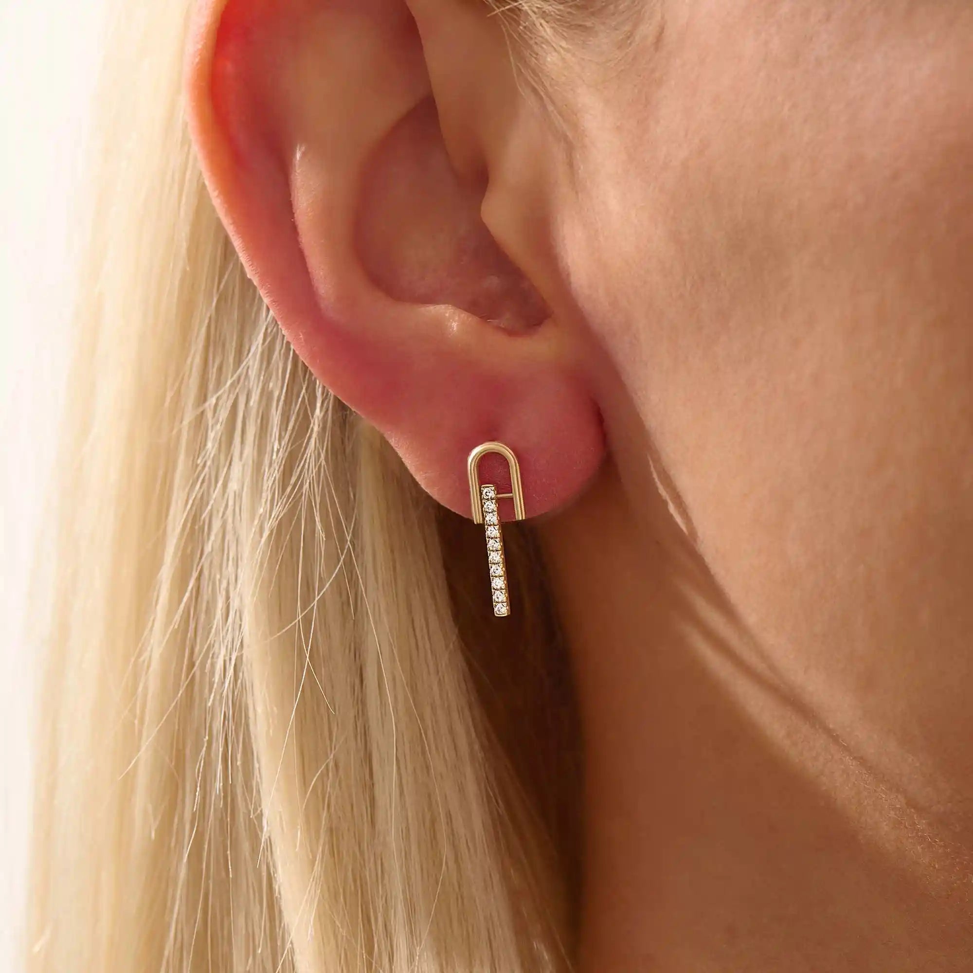 Close-up of a model wearing a 14k yellow gold U-top bar stud earring with a line of brilliant moissanite stones.
