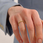 Close-up of a woman wearing a 14k solid yellow gold bamboo-inspired wedding band with evenly spaced moissanites