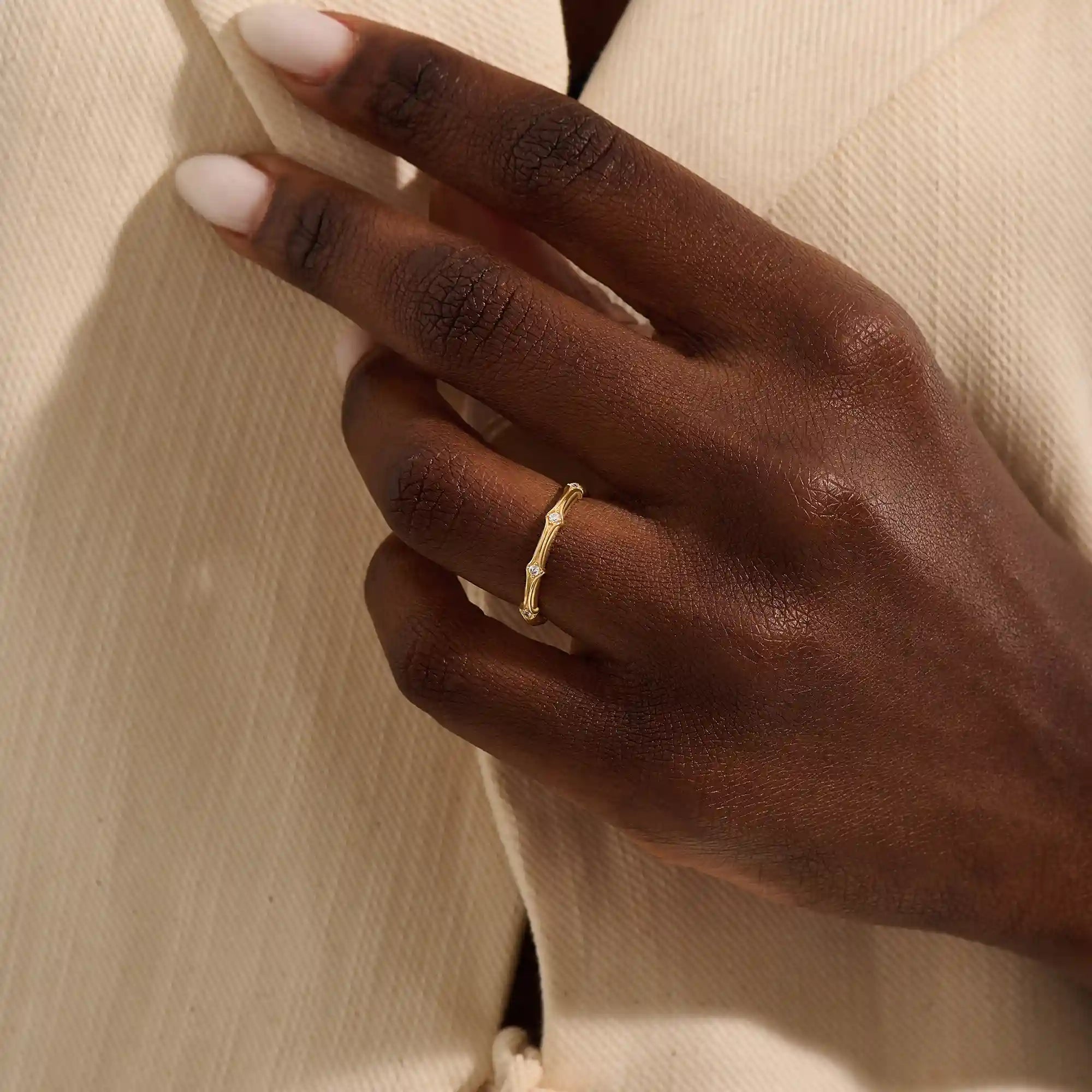 Close-up of a woman wearing a 14k solid yellow gold bamboo-inspired wedding band with evenly spaced moissanites
2