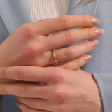 Close-up of a woman wearing a 14k solid yellow gold bamboo-inspired wedding band with evenly spaced moissanites