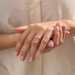 Close-up of a woman wearing a 14k solid yellow gold band with a baguette cut moissanite center stone and round brilliant cut moissanite accents, minimal and modern fine jewelry