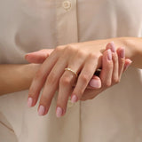 Close-up of a woman wearing a 14k solid yellow gold band with a baguette cut moissanite center stone and round brilliant cut moissanite accents, minimal and modern fine jewelry