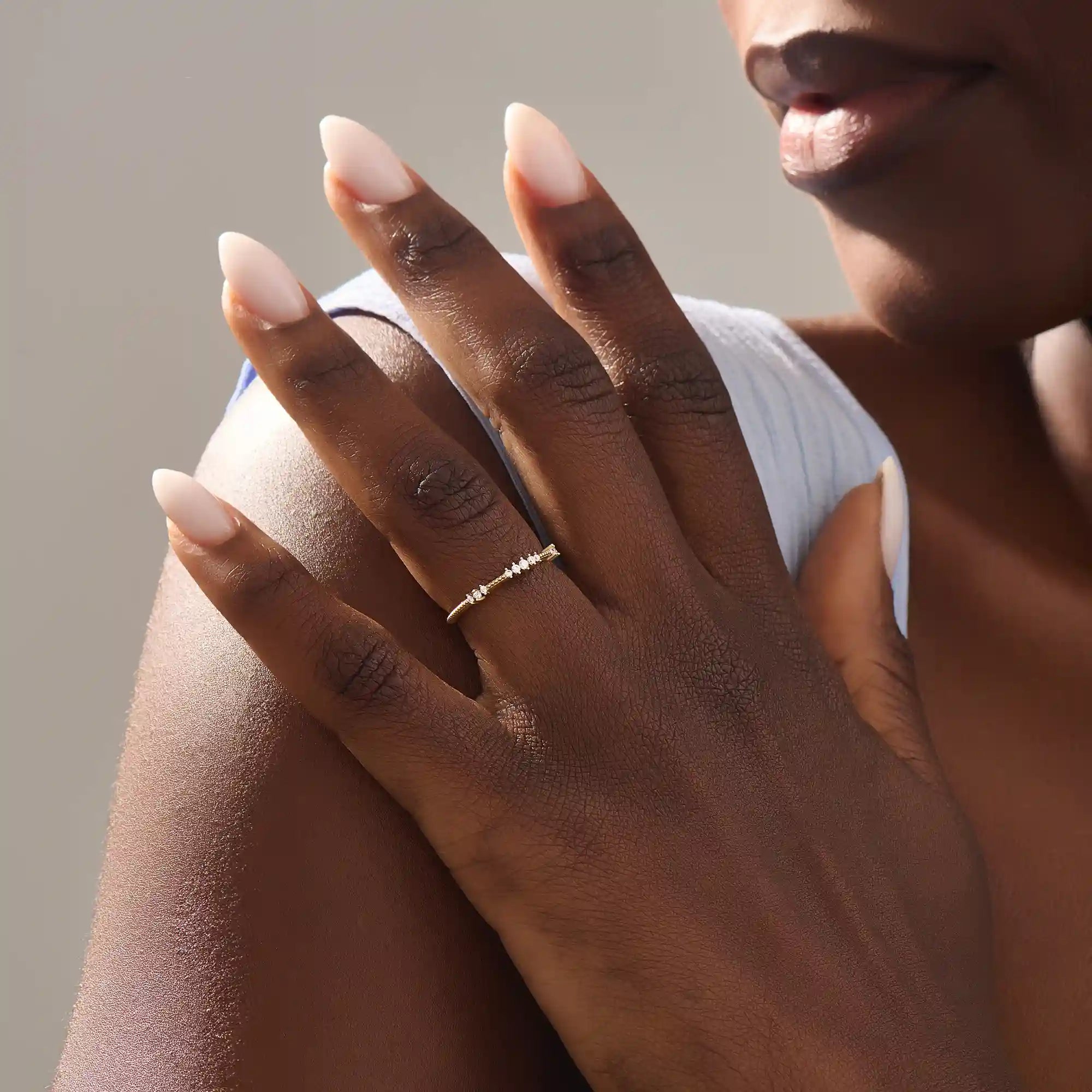 Close-up of a woman wearing a 14k solid yellow gold band with round brilliant cut moissanite stones in alternating prong and bead settings, minimal and elegant bridal jewelry