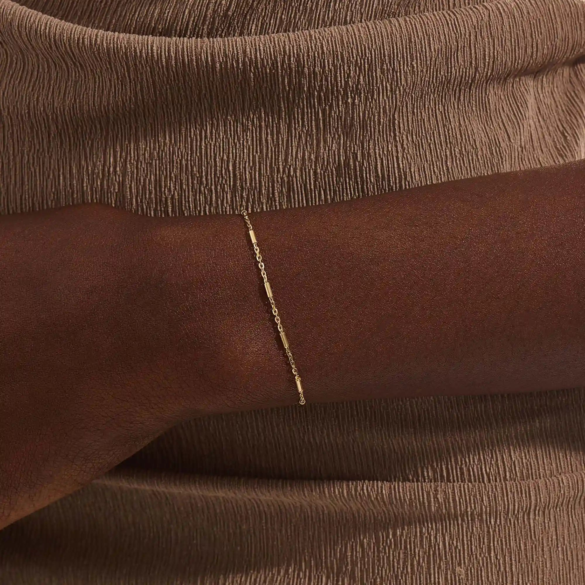 Close-up of a woman wearing a 14k solid yellow gold bar chain bracelet, its delicate design draping gracefully on the wrist for a refined everyday look.