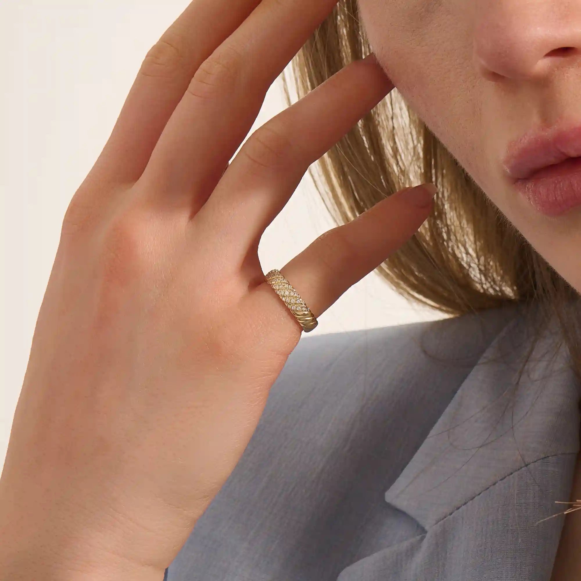 Close-up of a woman wearing a 14k solid yellow gold dome band with rows of pavé set round brilliant cut moissanite stones, luxurious and elegant wedding or statement ring