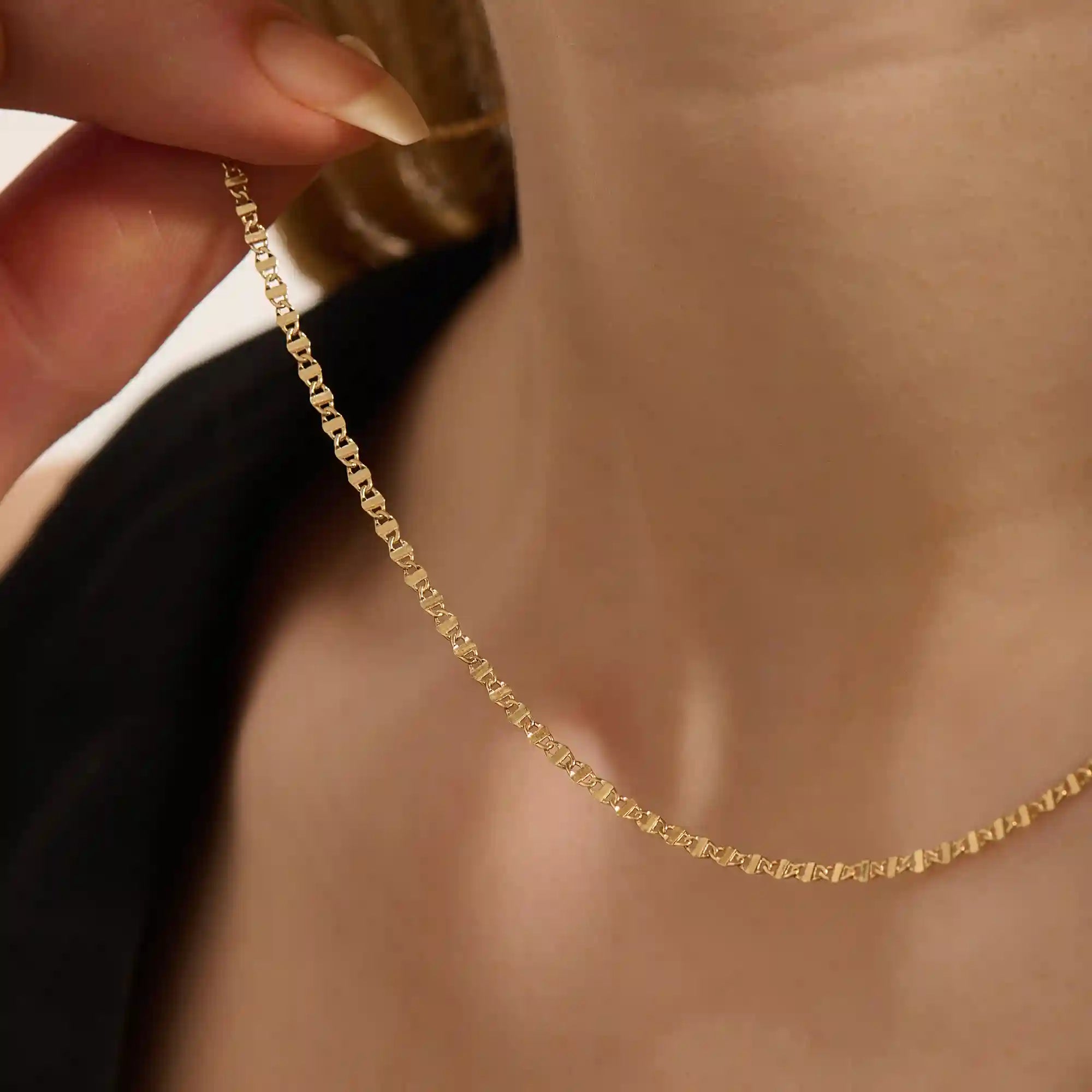 Close-up of a woman wearing a 14k solid yellow gold mariner chain necklace, styled alone to showcase its classic interlocking link pattern and refined shine.