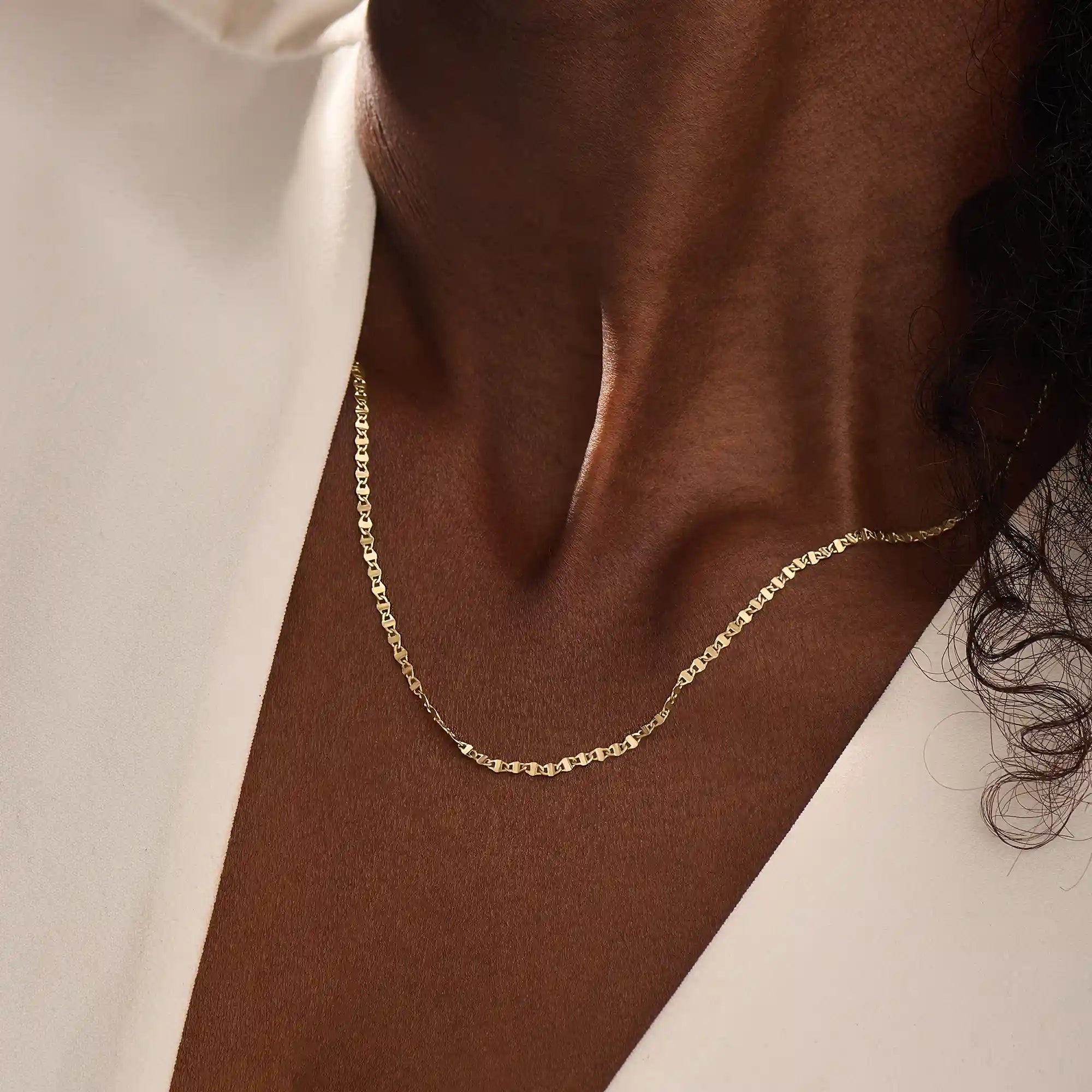 Close-up of a woman wearing a 14k solid yellow gold mariner chain necklace, styled alone to showcase its classic interlocking link pattern and refined shine.
2