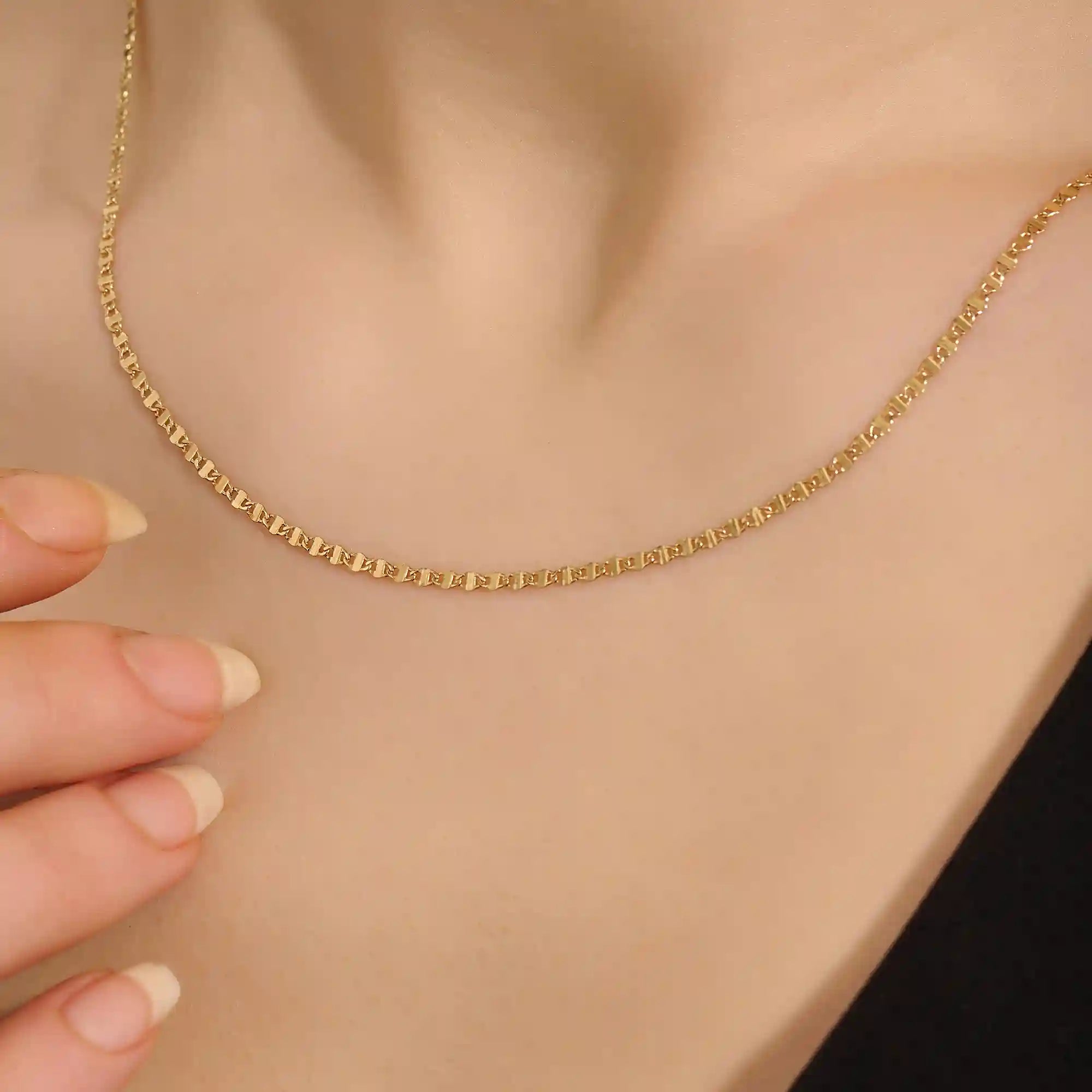 Close-up of a woman wearing a 14k solid yellow gold mariner chain necklace, styled alone to showcase its classic interlocking link pattern and refined shine.