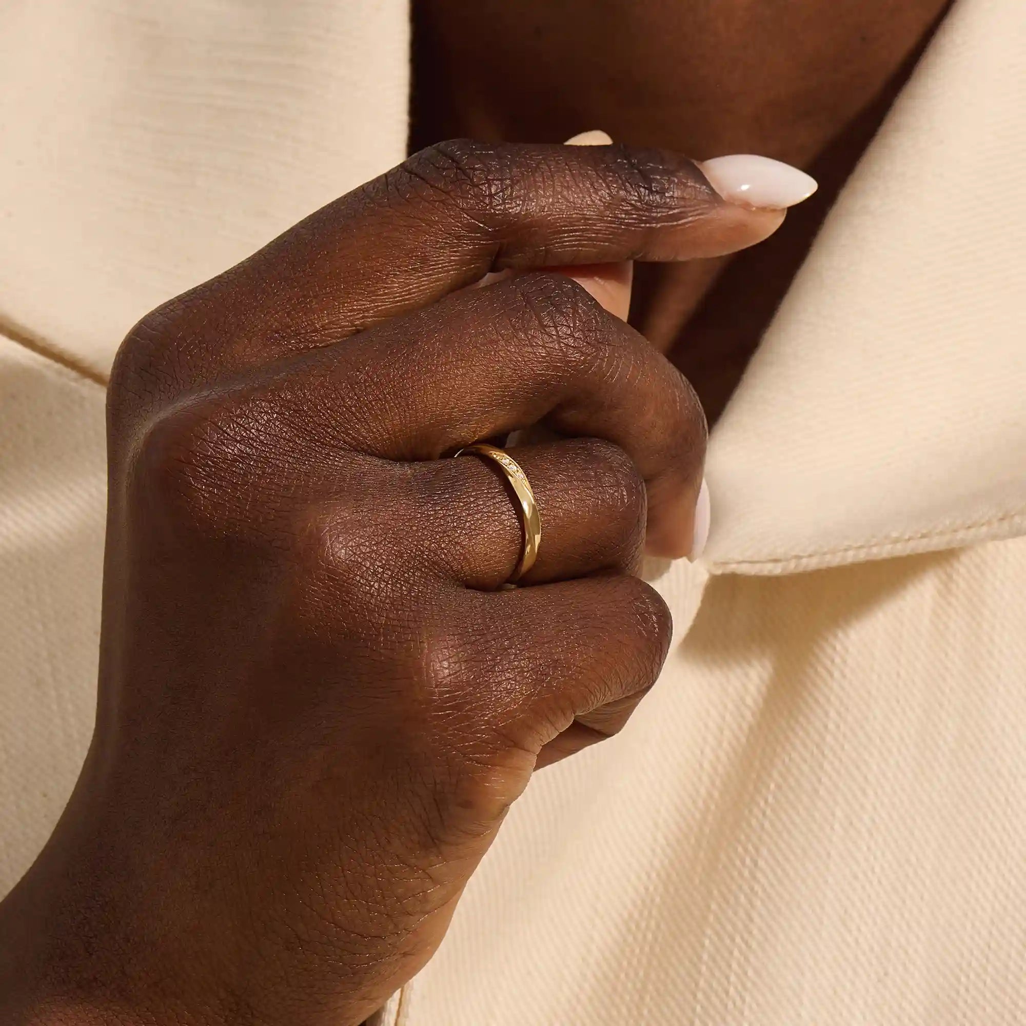 Close-up of a woman wearing a 14k solid yellow gold twisted wedding band with a cluster of round moissanites in a marquise-shaped opening, elegant and timeless
4