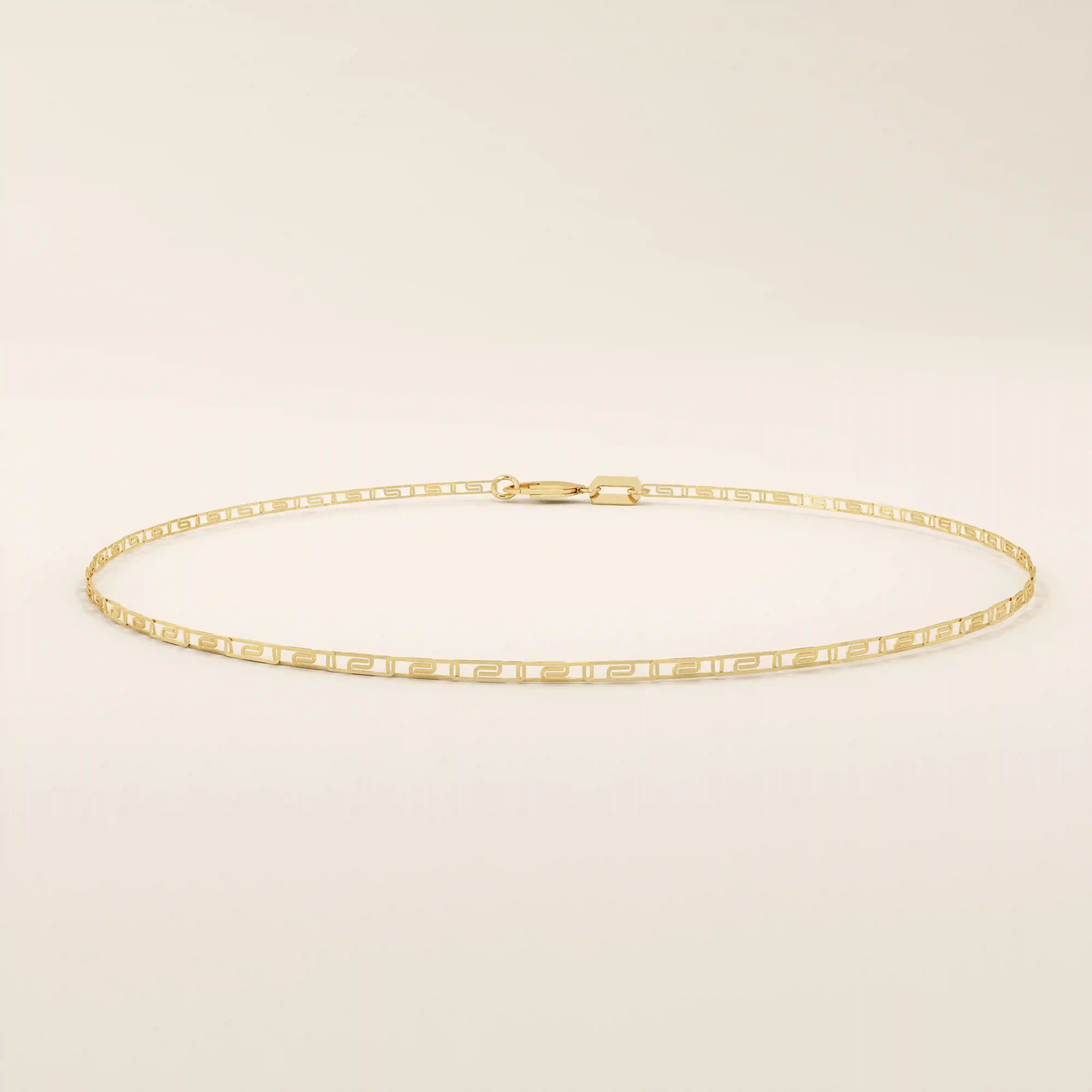 Close-up view of a 14k gold scroll chain bracelet showing the fine engraved rectangular scroll links.