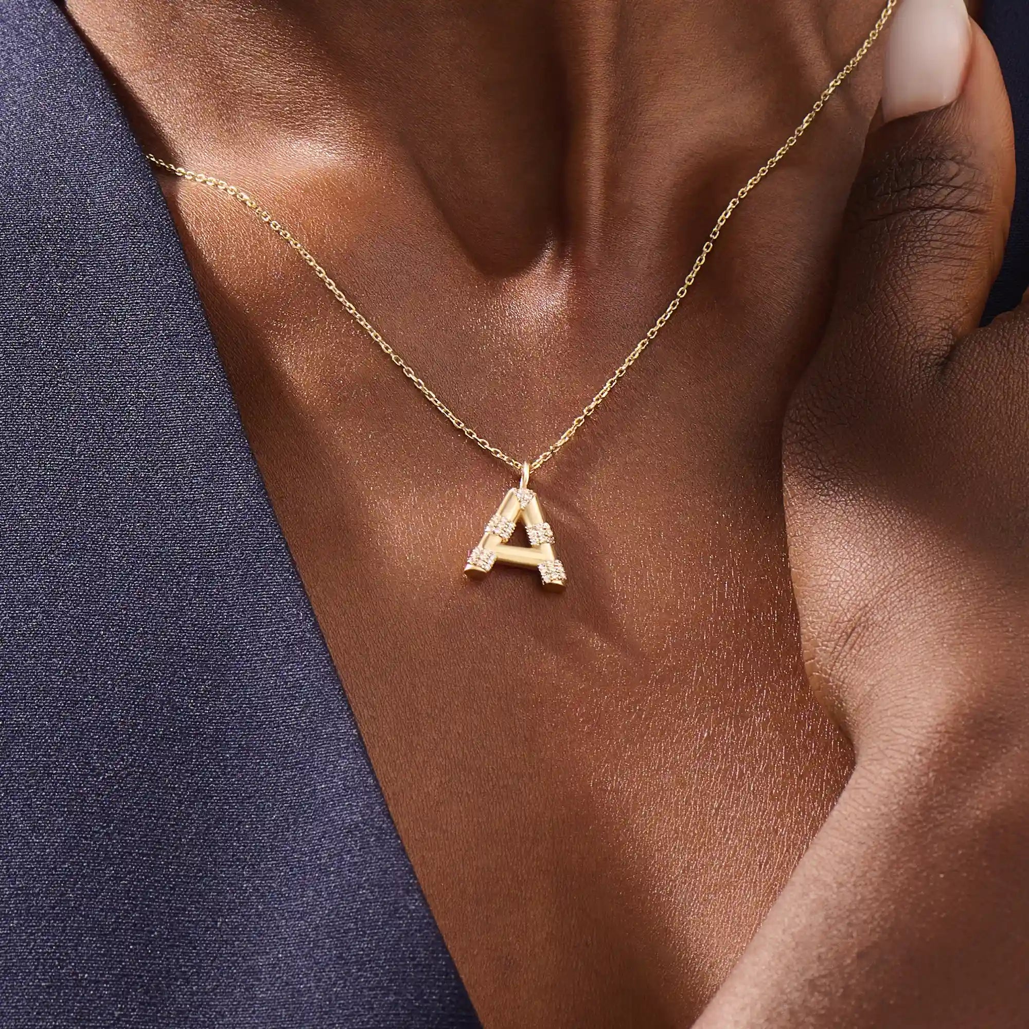 Model showcases a bold pavé initial necklace in 14k gold, sparkling with moissanite stones. Perfect for layering or gifting with impact.