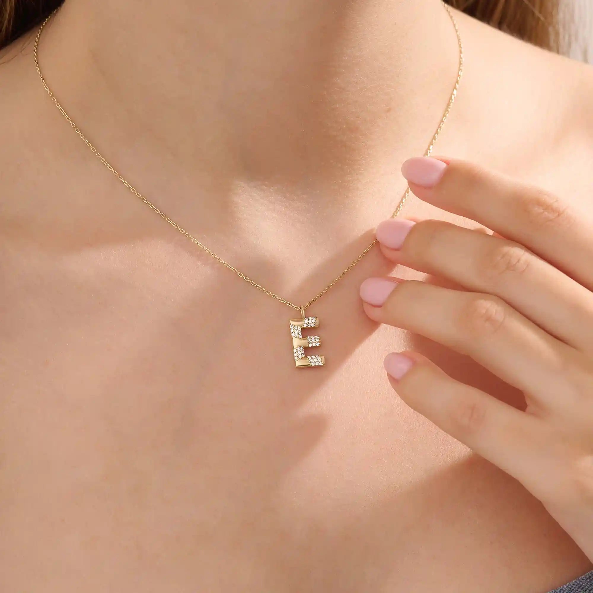 Model showcases a bold pavé initial necklace in 14k gold, sparkling with moissanite stones. Perfect for layering or gifting with impact.