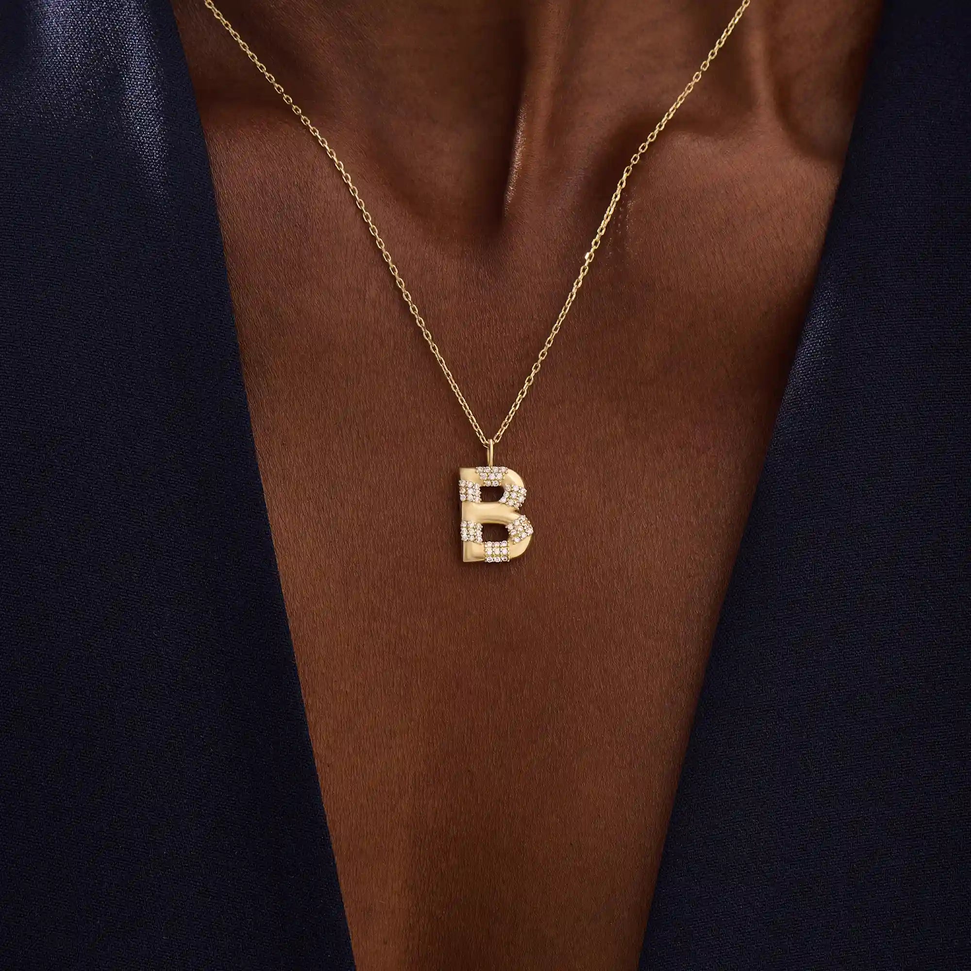 Model showcases a bold pavé initial necklace in 14k gold, sparkling with moissanite stones. Perfect for layering or gifting with impact.