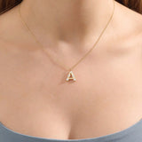 Model showcases a bold pavé initial necklace in 14k gold, sparkling with moissanite stones. Perfect for layering or gifting with impact.