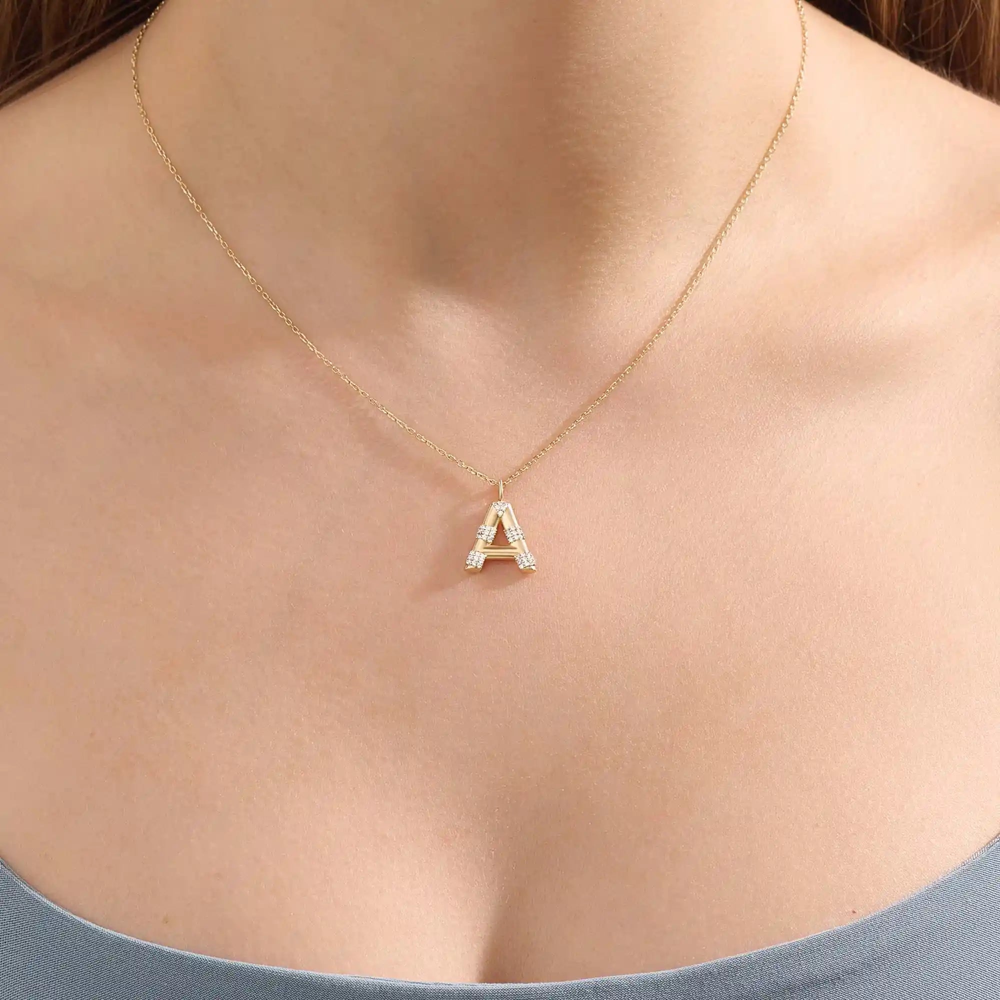 Model showcases a bold pavé initial necklace in 14k gold, sparkling with moissanite stones. Perfect for layering or gifting with impact.