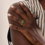 Model showcasing a 14k gold statement ring set with five pear-shaped emeralds. Striking and colorful gemstone ring perfect for standout looks.